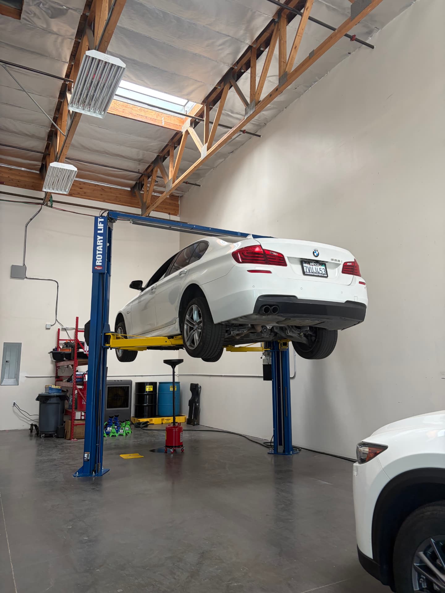 White BMW sedan on a Rotary lift inside Johnny's Auto Repair shop in Victorville CA