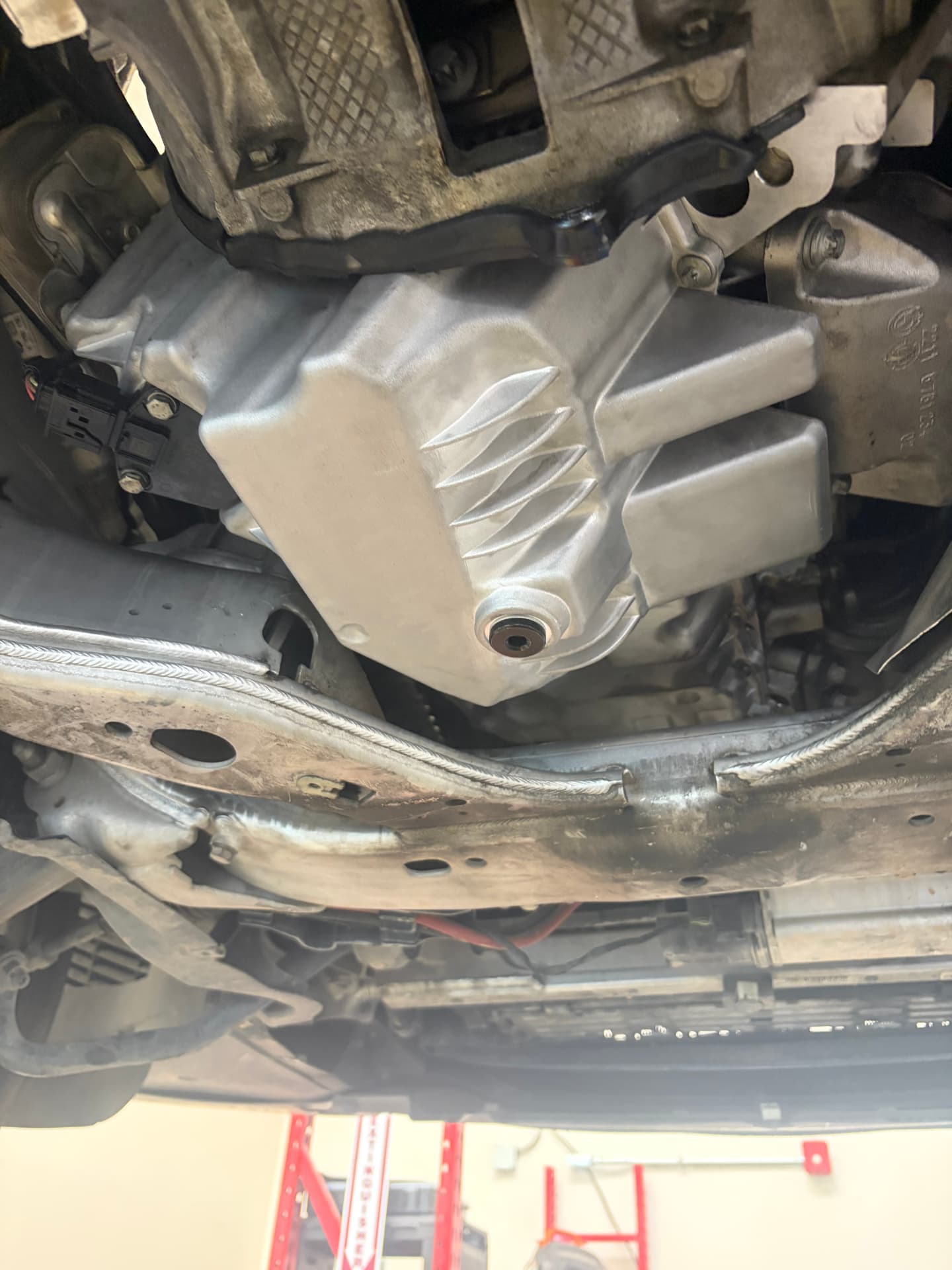 Close-up of a freshly installed oil pan under a BMW at Johnny's Auto Repair on Ridgecrest Road in Victorville CA